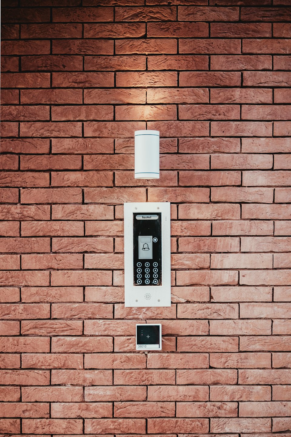 Kırmızı tuğla duvarda modern interkom sistemi.